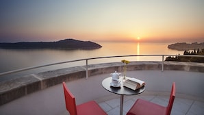 A terrace with a table set for tea, overlooking a calm body of water at sunset. - Luxury Residence Queen of Dubrovnik (Dubrovnik)