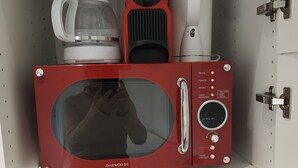 A compact kitchen with a red microwave, a coffee maker, and a coffee pot.