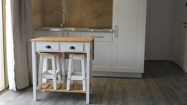 A modern kitchen with white cabinetry, a wooden countertop, and a built-in stove.
