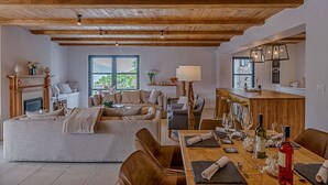 A spacious living area with a fireplace, sofas, a dining table set for a meal, and a kitchen in the background. - Beachfront Villa Feodora Grande (Korcula)