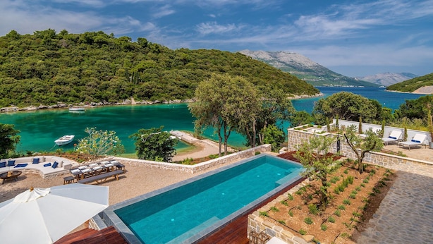 A pool with a view of a coastal area, surrounded by a lounge area with chairs and a sunbed. - Beachfront Villa Feodora Grande (Korcula)