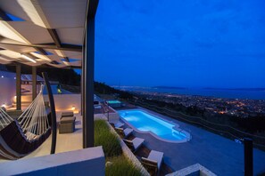A modern outdoor pool area with a view of the city at dusk. - Luxury Villa Grand View (Kastela)