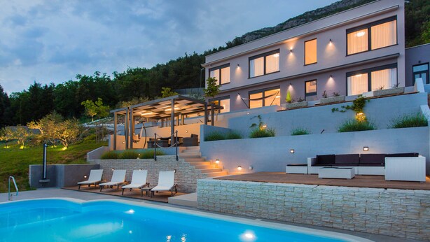 Une maison moderne dotée d’une piscine, d’un espace extérieur aménagé et d’un mur de soutènement en pierre.
