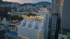 Un hotel con un cartel llamativo, arquitectura moderna y vistas de la ciudad circundante.