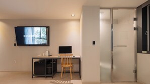 Una habitación moderna con escritorio, silla, televisor y una puerta.