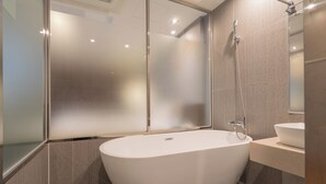 Un baño moderno con una bañera independiente, cabina de ducha con mampara de vidrio y un lavabo.