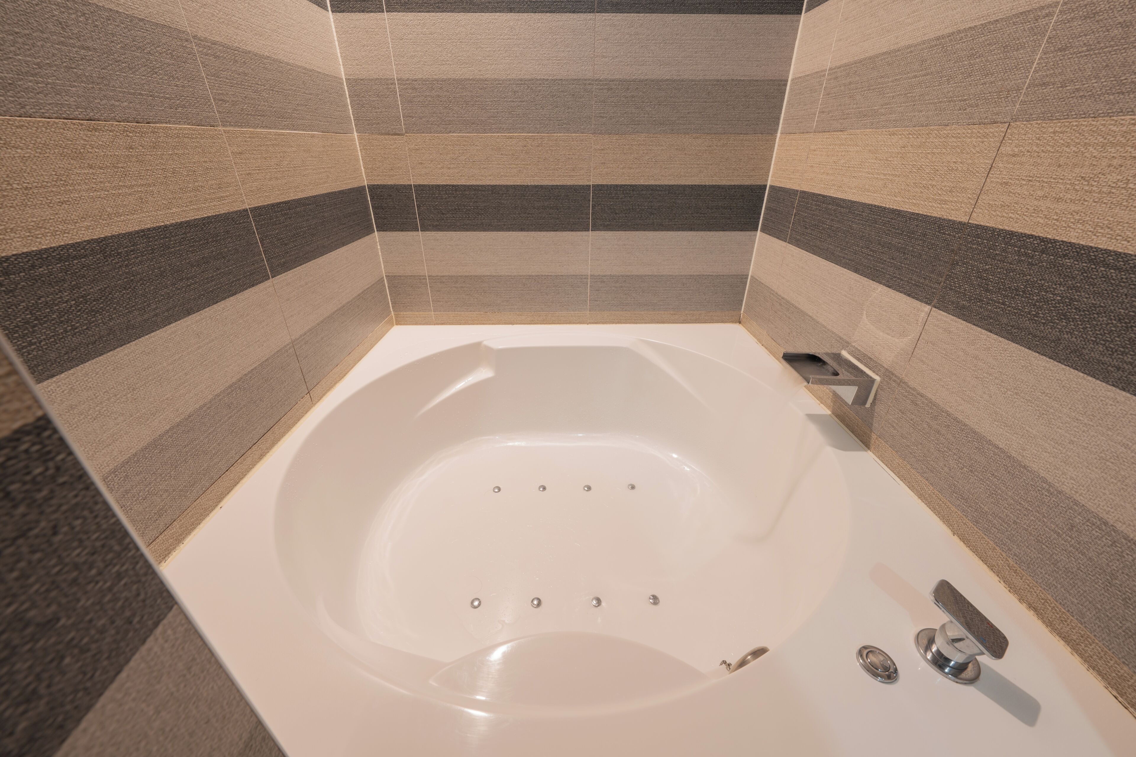 Un baño moderno con una bañera independiente, un cabezal de ducha de mano y un grifo instalado en la pared.
