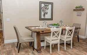 A dining area with a wooden table, white chairs, and a framed picture on the wall. - City Ranch - Valrico (Valrico)