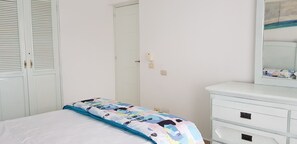 Une chambre à coucher avec un lit, une commode, un miroir et une porte.