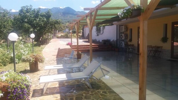 A covered outdoor area with a pool, lounge chairs, and a pergola.