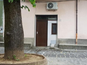 Un bâtiment avec une porte marron, une petite fenêtre et un climatiseur fixé au mur.