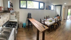 A kitchen with a wooden table, chairs, a stove, and a window.