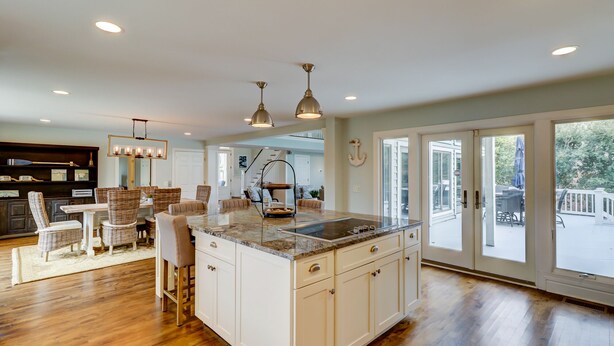 A spacious kitchen with a large island, white cabinetry, and a view to the outdoor patio.