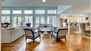 A spacious living room with a large window, a kitchen area, and a dining space.