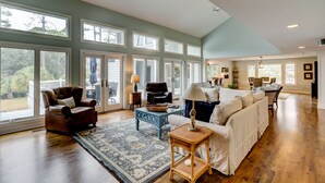 A spacious living room with large windows, a fireplace, and a dining area.