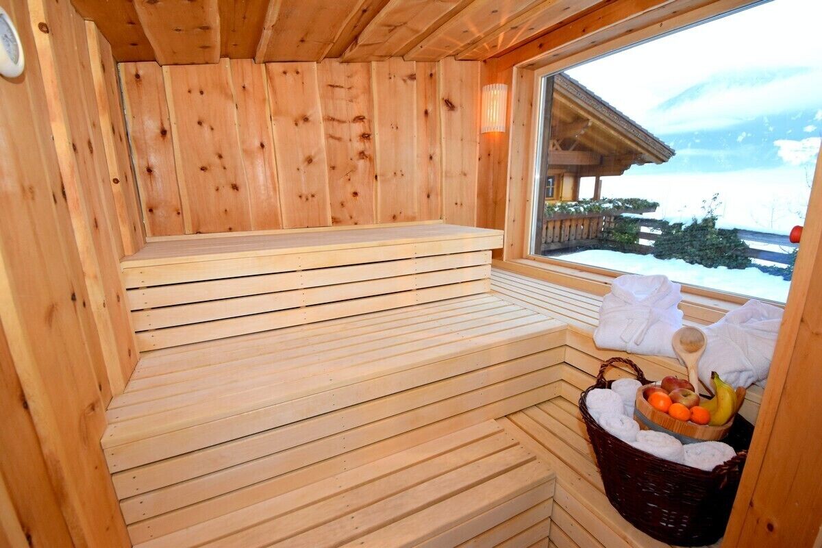 Un sauna en bois, doté de bancs et d’une fenêtre donnant sur un paysage enneigé.