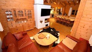 Interior acogedor de una cabaña de madera con chimenea, armarios de madera, zona de comedor y sofás de cuero.
