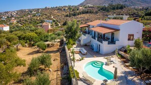 Una villa moderna con piscina, rodeada de un jardín ajardinado y vistas a la montaña.