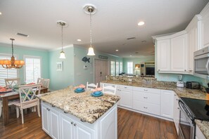 Enjoy meals in the kitchen with a central island, white cabinetry, and dining area.