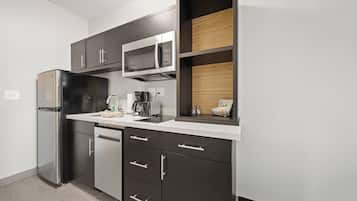Una cocina moderna con un refrigerador de acero inoxidable, un microondas y una cafetera.