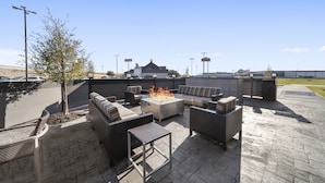 An outdoor patio area with a fire pit, seating, and a view of a building in the background. - TownePlace Suites by Marriott Waco Northeast (Waco)