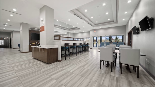 A spacious, modern hotel lobby with a reception desk, bar area, and seating for guests. - TownePlace Suites by Marriott Waco Northeast (Waco)