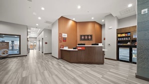 A reception area with a wooden reception desk, a refrigerator, and a sign that says "hello". - TownePlace Suites by Marriott Waco Northeast (Waco)