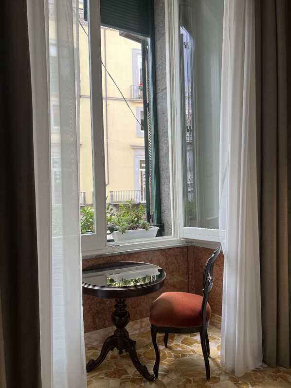 A corner room with a window, a table, and a chair.