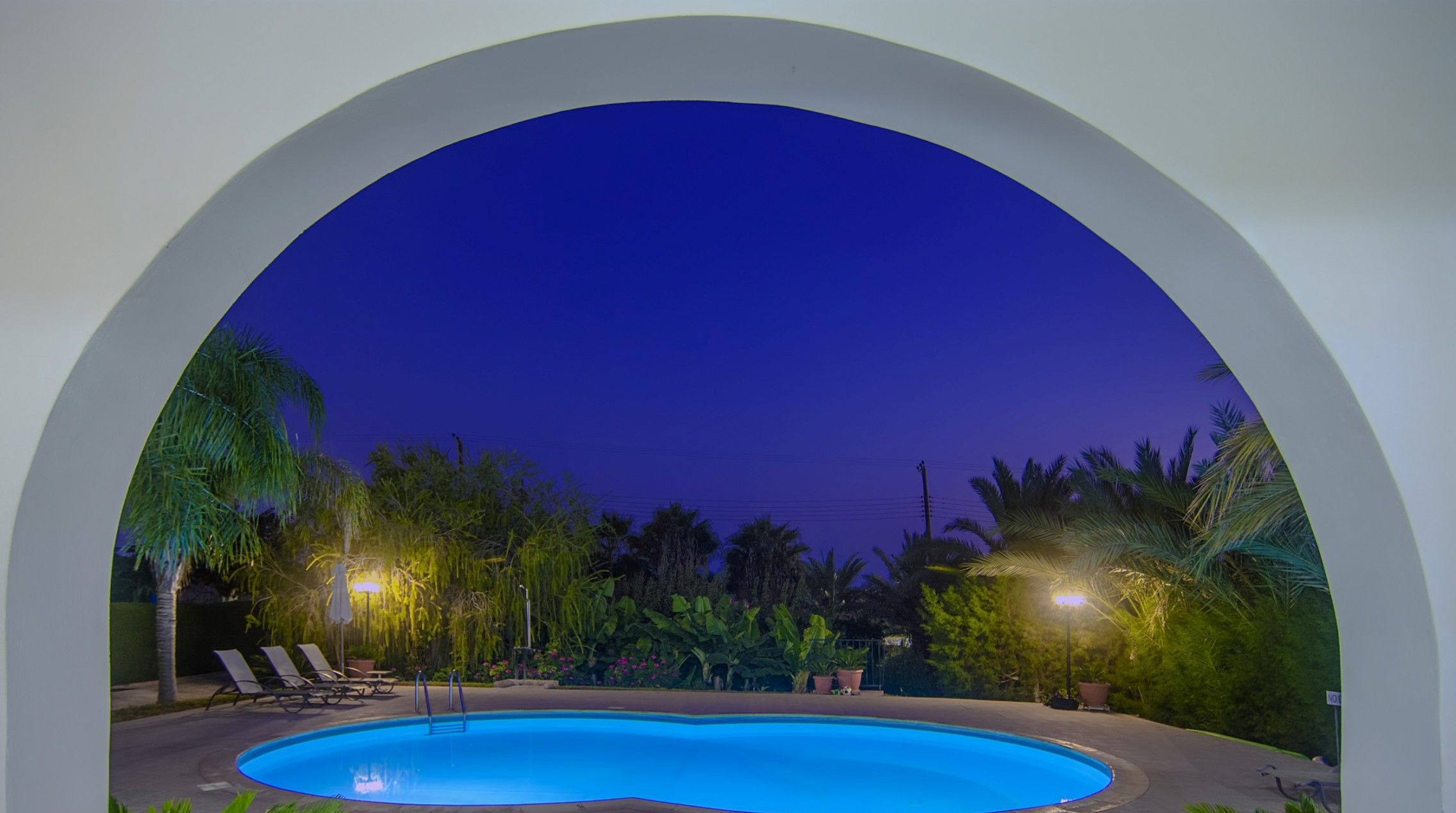 Una piscina en CoralSun Villas con sillas de descanso y plantas tropicales.