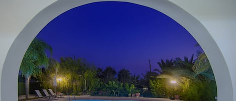 Una piscina en CoralSun Villas con sillas de descanso y plantas tropicales.