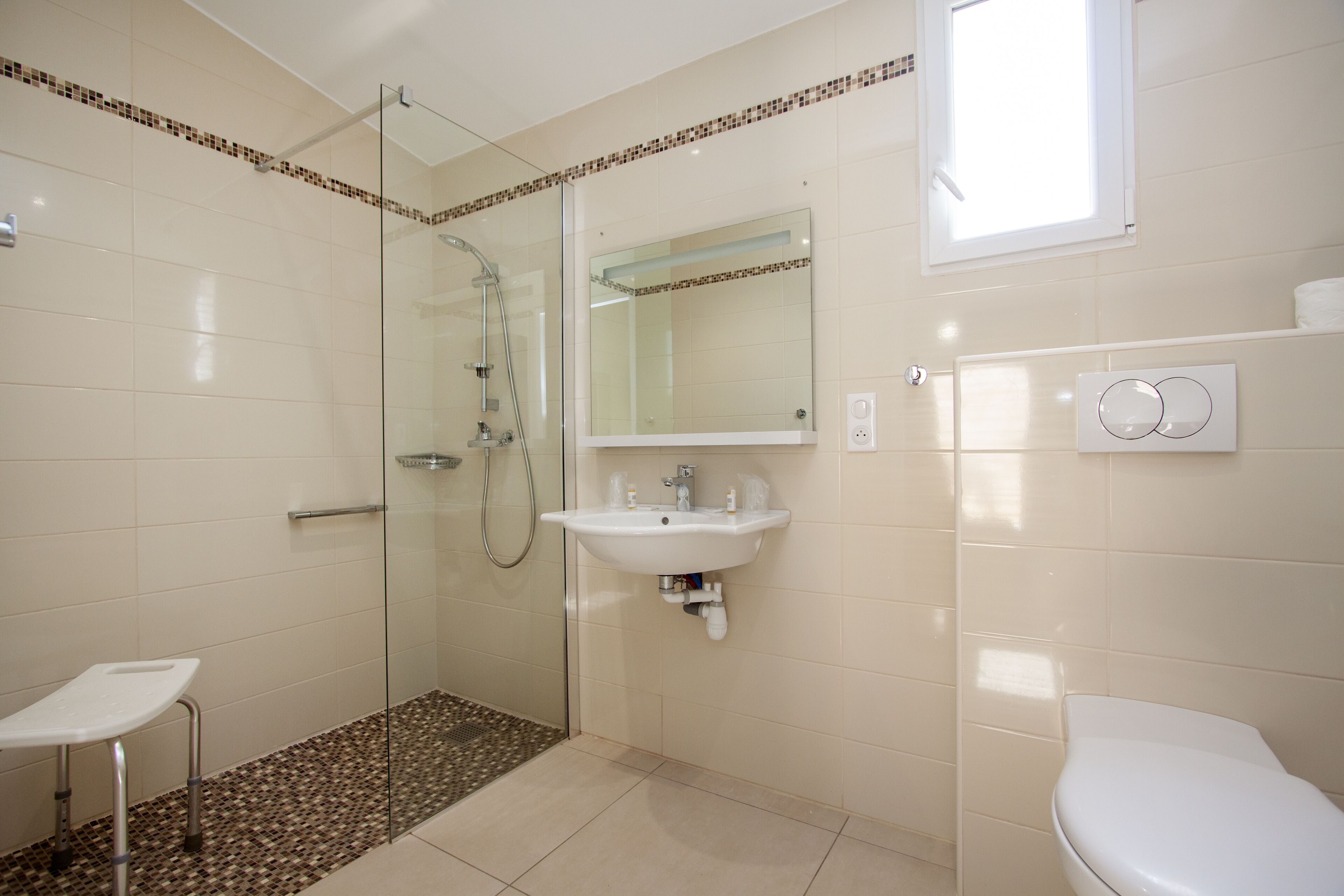 Ein Badezimmer mit Duschkabine aus Glas, Waschbecken, Toilette und Spiegel.