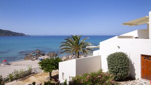 Un bâtiment situé sur la côte, offrant une vue sur la mer, avec un palmier et une terrasse carrelée.