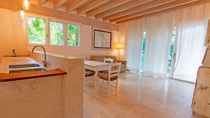 A kitchen with a sink, a dining table with chairs, a sofa, and a map on the wall. - Le Grotte Cottage with Pool Elba Island (Portoferraio)