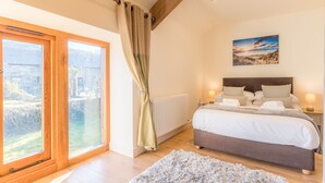 A bedroom with a large window, a bed with two bedside tables, and a radiator.