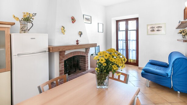 A kitchen with a white refrigerator, a wooden table, and a vase of yellow flowers. - Apartment The triangle near the center and the beach (Marina di Campo)
