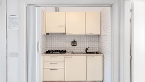 A compact kitchen with white cabinets, a tiled backsplash, a gas stove, and a sink. - Apartment The triangle near the center and the beach (Marina di Campo)