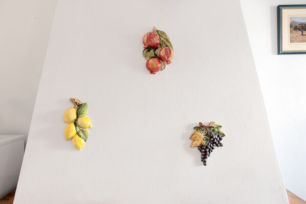 Una pared con tres adornos de frutas: limones, granadas y uvas.