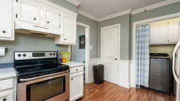 Una cocina con armarios blancos, una estufa de acero inoxidable y un refrigerador.