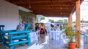 Un espace extérieur abrité, aménagé avec des tables et des chaises, doté d’un plafond en bois et agrémenté d’une plante en pot.