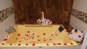 Une baignoire remplie de pétales de rose et une serviette ornée d’un motif en forme de cœur.