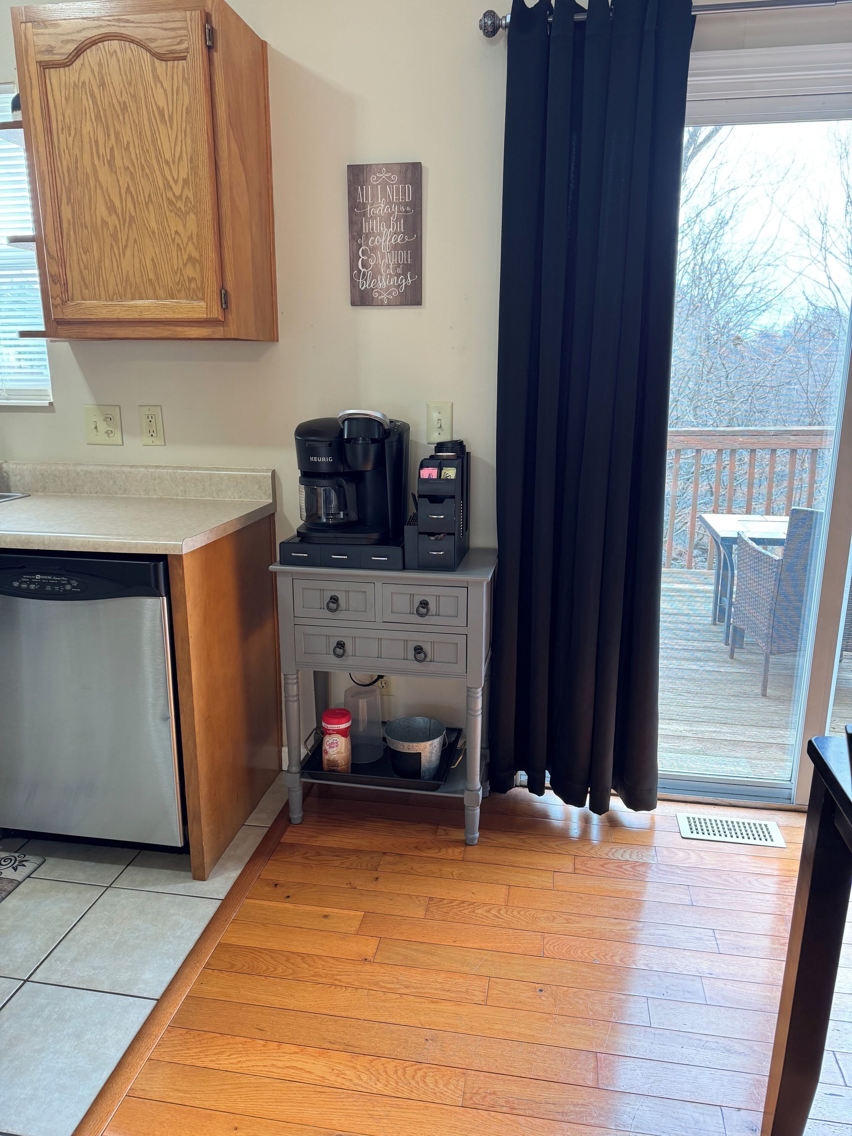 A kitchen with a coffee maker, a small cabinet, and a sign on the wall.