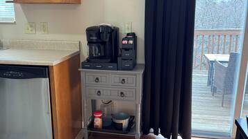 A kitchen with a coffee maker, a small cabinet, and a sign on the wall.