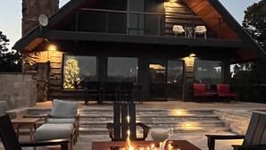 A modern house with a stone tower, outdoor seating, and a fire pit. - Charming Mountain Chalet with Stunning Views (Montrose)