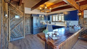 A rustic kitchen with wooden beams, a large island, and modern appliances. - Charming Mountain Chalet with Stunning Views (Montrose)