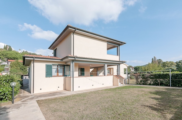 A two-story house with a balcony, a small garden, and a clear sky.