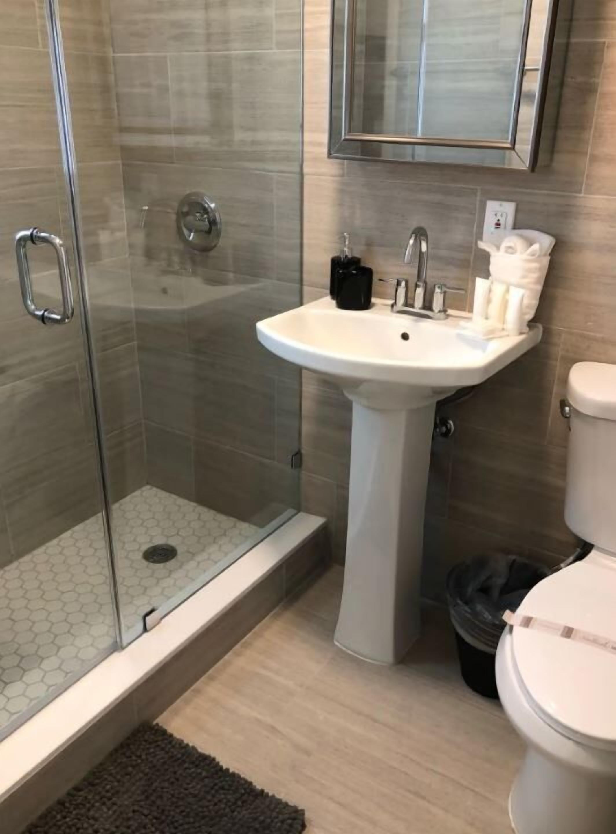 Ein modernes Badezimmer mit einer Duschkabine, einem weißen Waschtisch und einer Toilette.