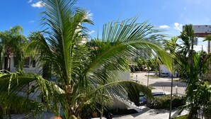 En boligbygning med altaner, palmer og en bysilhuet i baggrunden.