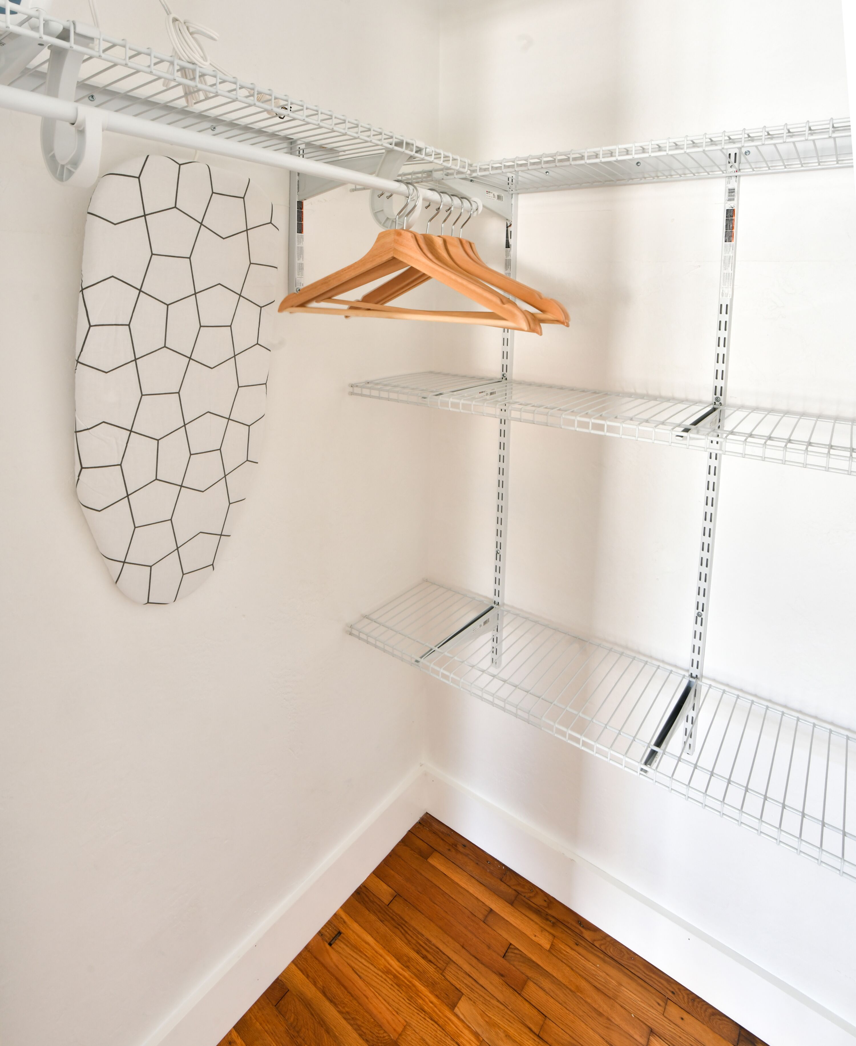 A walk-in closet with metal shelving units and a wooden hanger.