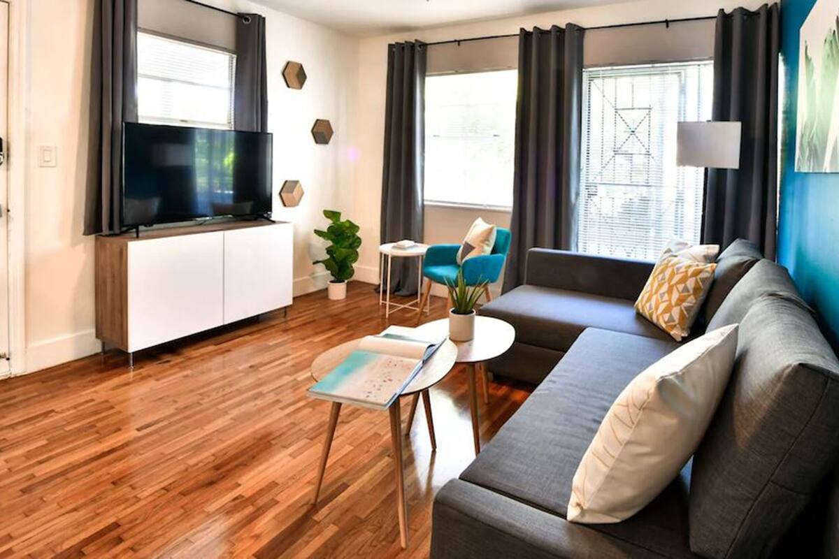Een moderne woonkamer met een flatscreen televisie, een bank, een salontafel en een klein bijzettafeltje.
