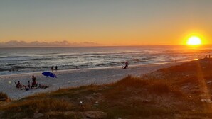 A beach scene with people relaxing and walking along the shore. - You in Paradise in Arraial do Cabo, amazing house facing the beach. Do not miss it !! (Arraial do Cabo)